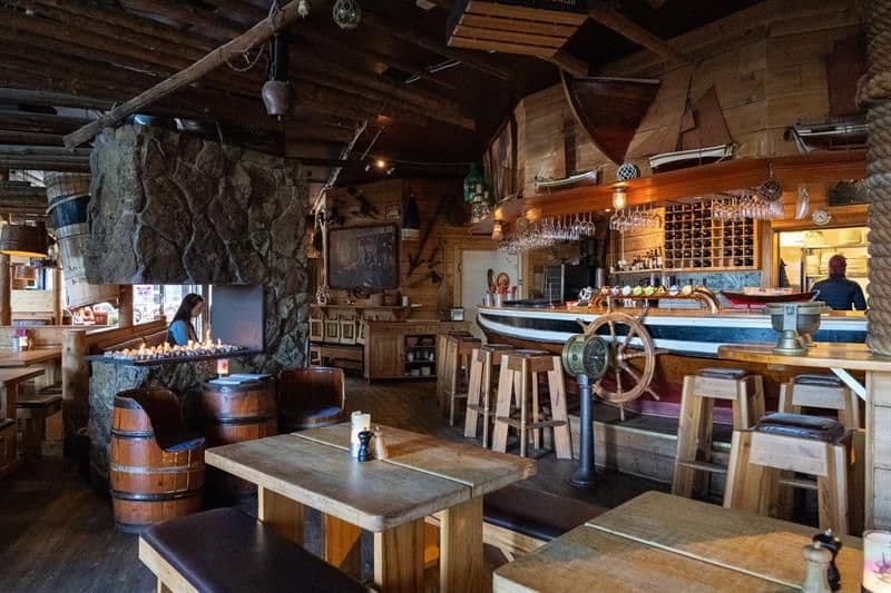 Hyggelig interiør med bardisk og kjøkken i bakgrunnen.